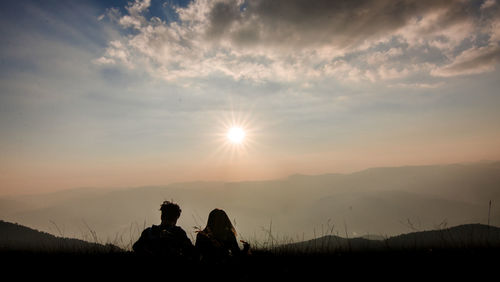 Silhouette people on mountain against sky during sunset