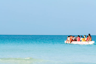 People at sea shore against clear sky