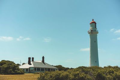 Low angle view of lighthouse by building against sky