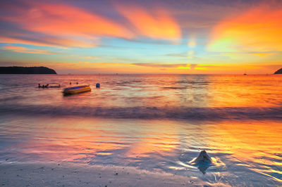 Scenic view of sea against dramatic sky during sunset