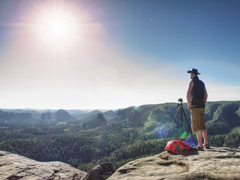 Cowboy hiker at camera on tripod, looking into landscape and thinking. man with leather cowboy hat