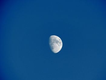 Low angle view of moon against blue sky at night