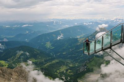 High angle portrait of woman standing on overhead cable car over mountains