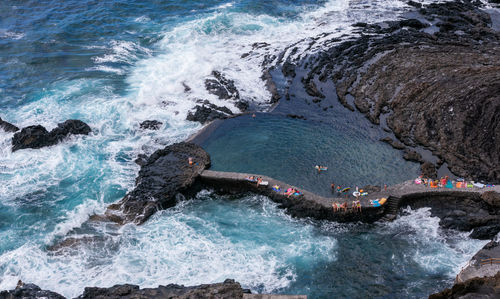 High angle view of sea waves splashing on rocks