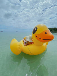 Rear view of girl enjoy the rubber yellow duck on the sea