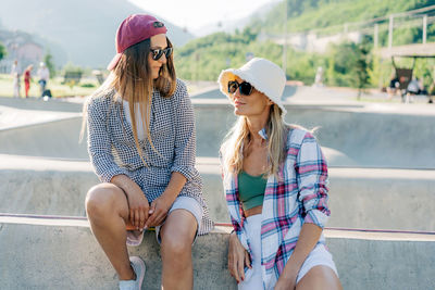 Two women are talking while sitting in a skatepark.