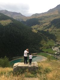 Rear view of man with boy photographing mountains against sky