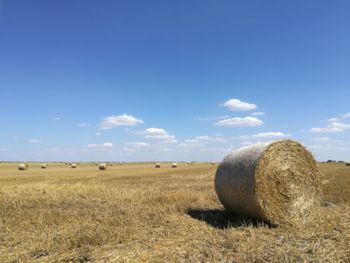 Hay bales on field against sky