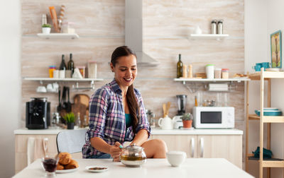 Portrait of young woman sitting in kitchen