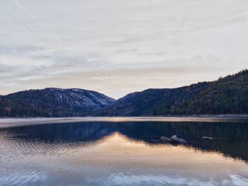 Scenic view of calm sea against mountain range