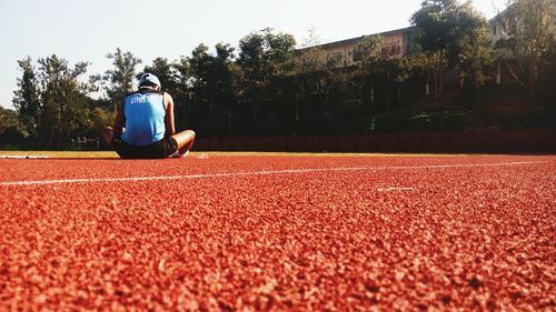 Rear view of athlete sitting on sports track