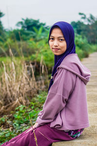 Portrait of young woman standing against trees