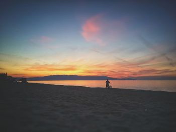 Silhouette man on beach against sky during sunset