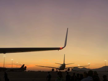 Silhouette people at airport against sky during sunset