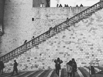 People on street against wall in city