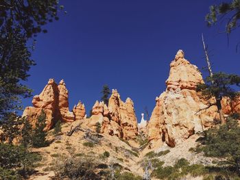 Low angle view of rock formation against clear blue sky