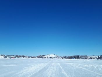 Snow covered road against clear blue sky