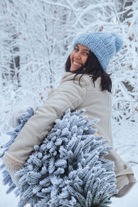 Portrait of smiling young woman wearing warm clothing standing amidst plants