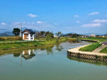 Houses by lake and buildings against sky