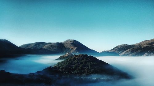 Scenic view of lake and mountains against clear blue sky