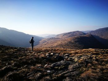 Man standing on dramatic landscape against clear sky