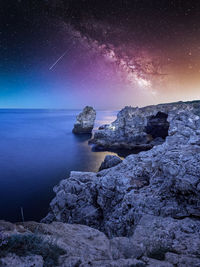 Rocks in sea against sky at night