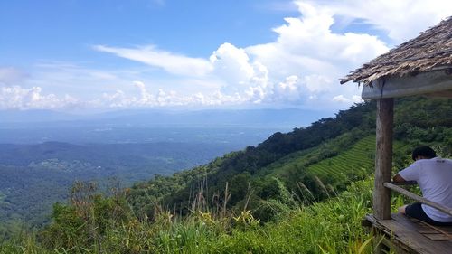 Rear view of man looking at landscape against sky