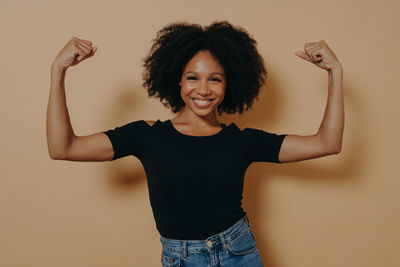 Portrait of smiling young woman against wall