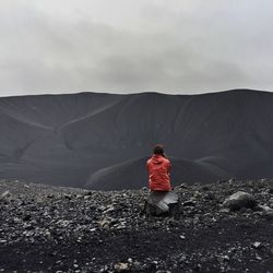 Person standing on mountain road against sky
