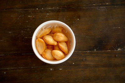 A bowl was of sala seedless in syrup with ice on the wood table.