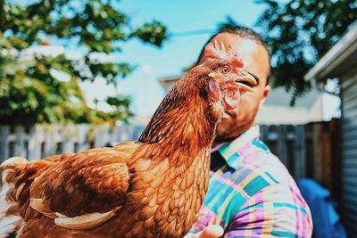 Man holding chicken in yard