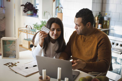 Father teaching online shopping to daughter on laptop at home