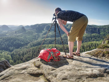 Hiker photographer framing picture with the face on the camera and looking through viewfinder