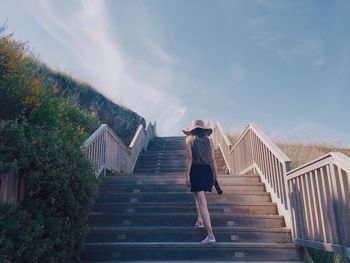 Rear view of woman on staircase against sky