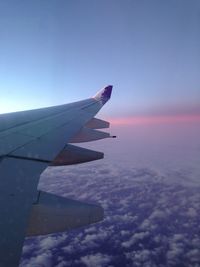 Airplane wing against sky during sunset