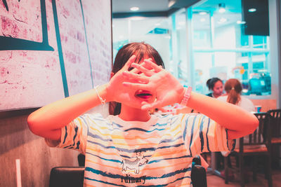 Young woman covering face in cafe