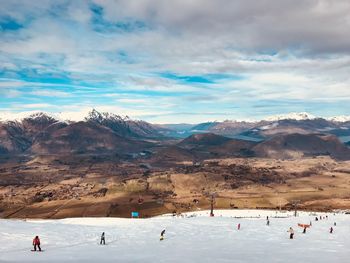 Group of people on snowcapped mountain against sky