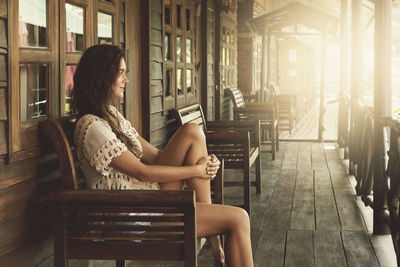 Side view of woman sitting on bench