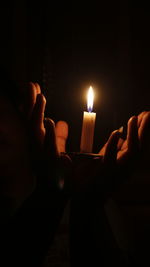 Close-up of hand holding lit candles