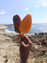 Midsection of person holding ice cream on beach