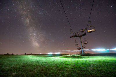 Chair lift on field against sky at night