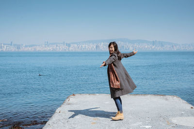 Rear view of woman standing at beach against clear sky