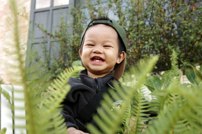 A happy little baby is smiling with blur fern on foreground