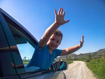 Portrait of boy in car against blue sky