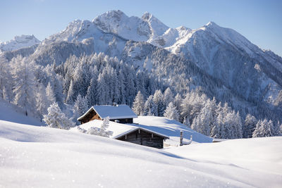 Beautiful winter mountain landscape with snowy forest and traditional alpine chalet