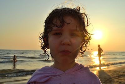 Portrait of cute boy on beach against sky during sunset