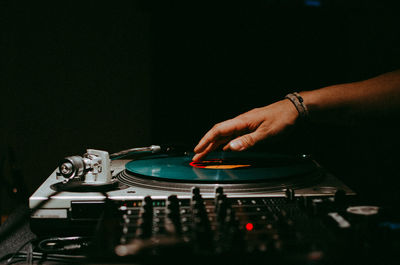 Close-up of hand playing turntable in darkroom