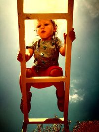 Low angle view of girl sitting against sky