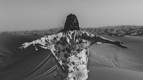 Rear view of woman on beach against sky