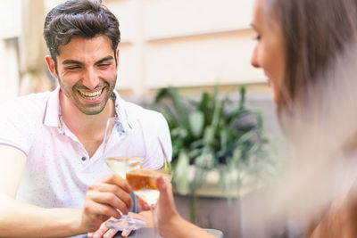 Smiling man toasting drinking glass with woman outdoors